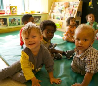 A group of racially diverse toddlers play on a mat at Toronto's Massey Centre.