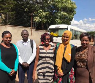 Four women and one man pose together in a Nairobi street. All are well dressed and workers for refugee assistance program.