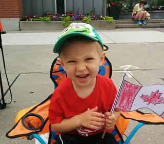 A young boy waves a Canada flag enthusiastically at a Canada Day celebration.