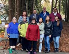 Ten people from the Indigenous Ministries and Justice staff gather for a photo in the British Columbia forest.