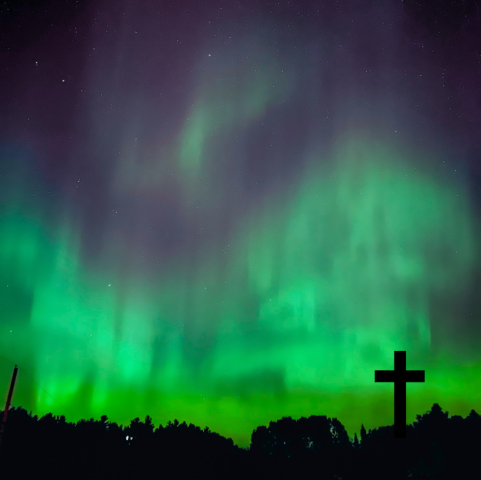 A cross silhouetted against the Northern Lights.