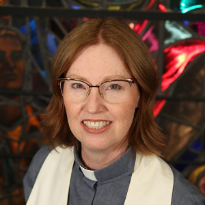 Moderator Kimberly Heath smiling, standing in front of stained glass