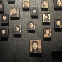 A wall hung with black and white photos of Chinese men and women from the 20th century.