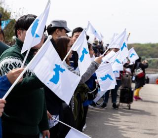 People gathered wave flags with a picture of a unified Korea and form a human peace chain in the Korean Peninsula