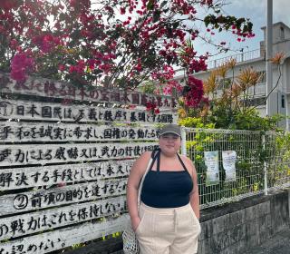 Ashley Keeping stands in front of a sign in Japanese