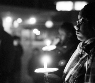 A man stands with a candle during a night time vigil.