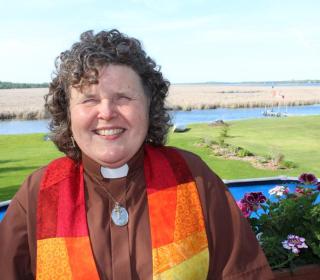 Sharon Ballantyne wearing a colourful minister's stole across her shoulders. Sharon Ballantyne is ministry personnel, serving a rural pastoral charge about two hours northeast of Toronto. A 2018 McGeachy Senior scholar, her work is focusing on equity. 