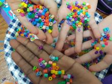 Children's hands holding lots and lots of multi-coloured beads.