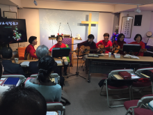 A small group of Korean women, wearing festive red sweaters, lead worship at a church in South Korea.