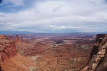 A photo looking down into a vast reddish canyon in the desert of Utah.