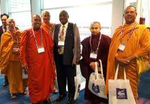 The author Leonard Mtaita from Tanzania, stands posing in the middle of a group of saffron-robed Buddhist monks at the Parliament of the World's Religions