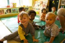 A group of racially diverse toddlers play on a mat at Toronto's Massey Centre.
