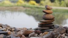A rock sculpture tower balances gracefully beside a river.