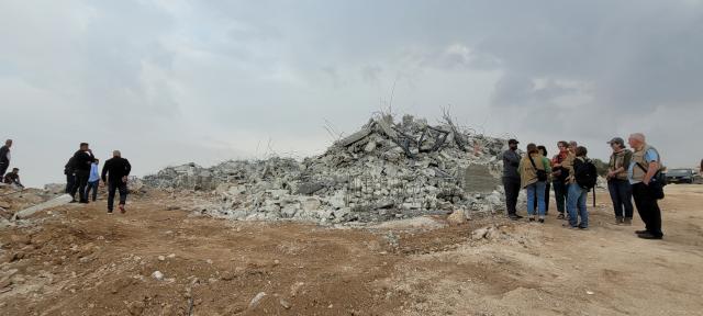 A huge pile of concrete rubble mark all that is left of the K. family home after demolition. Groups of people are seen standing around the pile, including Ecumenical Accompaniers.