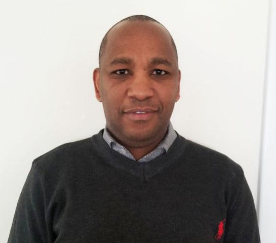 Rev. Andrew Kinoti Lairenge A portrait of Rev. Andrew Kinoti Lairenge, a middle-aged Black man with very short hair and kind eyes. Slightly smiling.