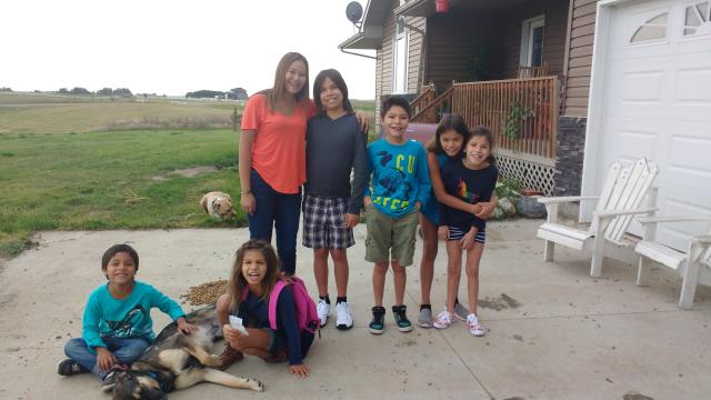 A group of First Nations siblings gathered together in a yard.