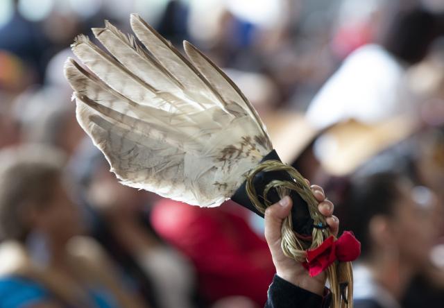 A red ribbon attached to an eagle feather is held up during ceremonies marking the release of the Missing and Murdered Indigenous Women report in Gatineau, June 3, 2019. Photo of an eagle feather held up during ceremonies marking the release of the Missing and Murdered Indigenous Women report in Gatineau, June 3, 2019