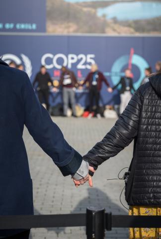 Demonstrators form a “human chain” calling for climate justice and urgent action from world leaders at COP25 in Madrid, December 2019. People hold hands while standing to form a human chain in front of a banner that reads COP25.