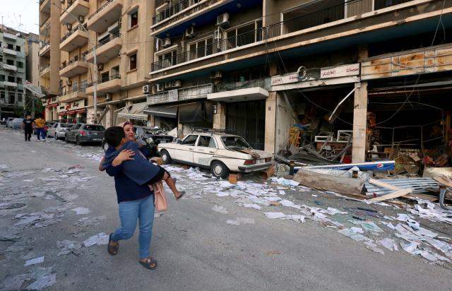 A woman carries a child through the streets of Beirut, Lebanon after the explosion. Woman and child in Beirut, Lebanon