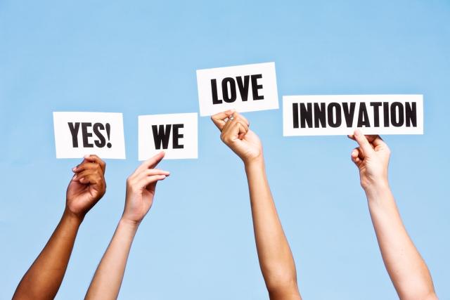 Hands holding up signs that read "Yes, we love innovation"